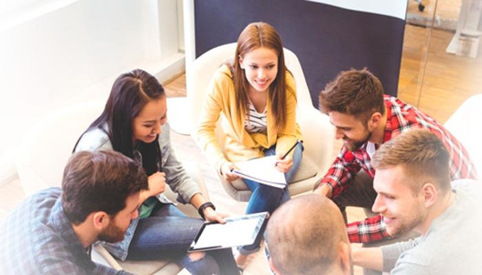 Colleagues use tablet while discussing strategies in creative office - How to start a part-time business that works - Image