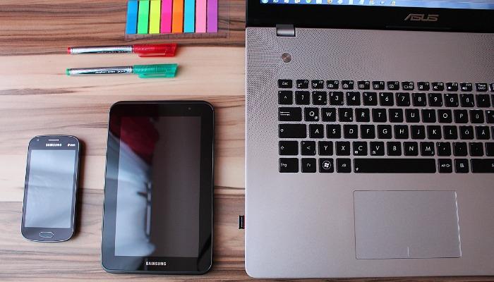 Vista superior de uma mesa de madeira com um telefone, tablet, canetas e laptop sobre ela - As melhores dicas de marketing em mídias sociais para iniciar e crescer seu negócio - Imagem